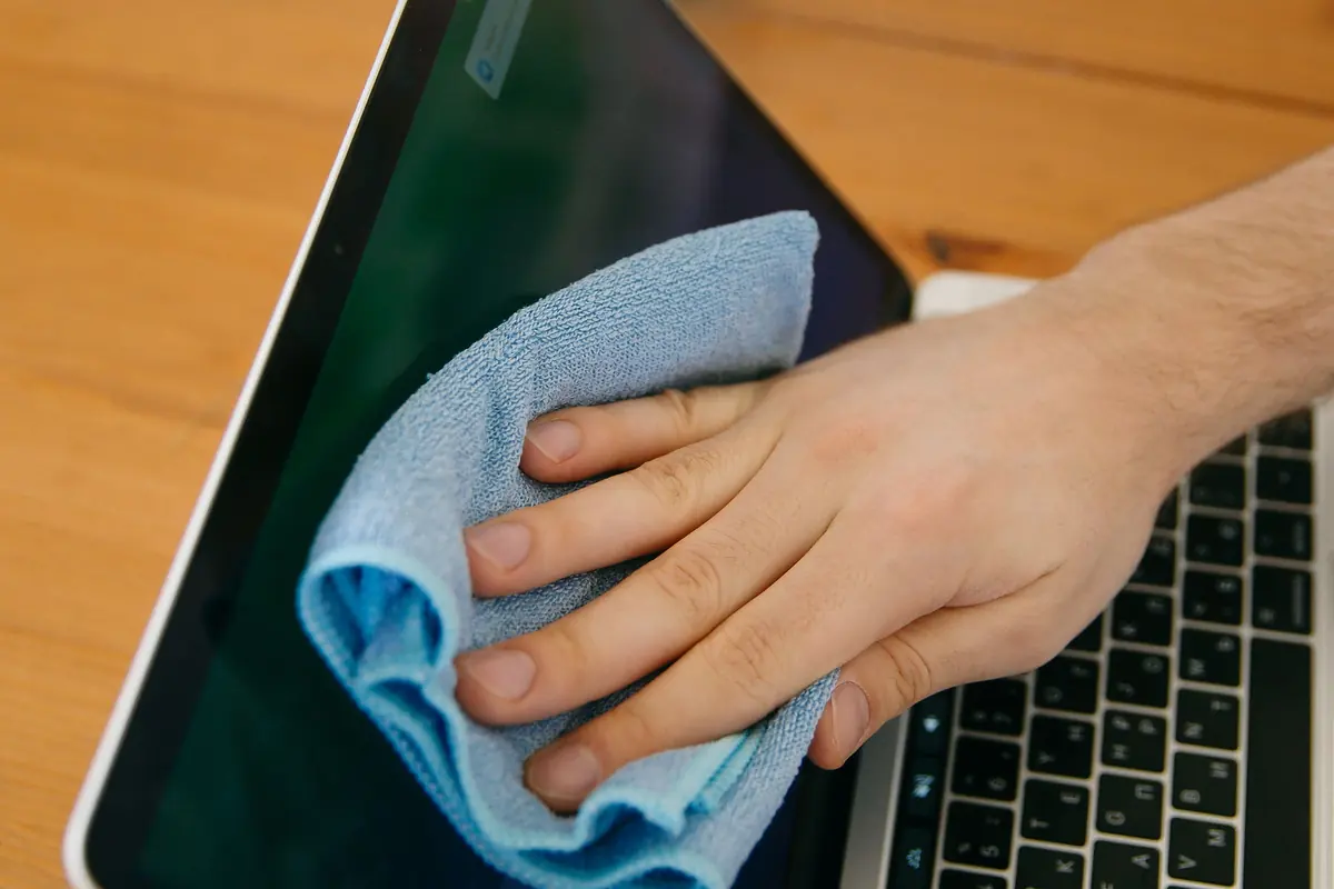Ofis temizliğinde dizüstü bilgisayar ve çalışma masasının mikrofiber bezle silinmesi